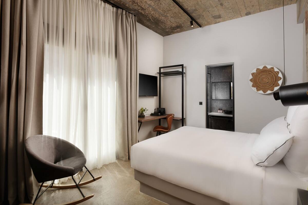Een moderne hotelkamer met een bed, een bureau, een stoel en een televisie.
