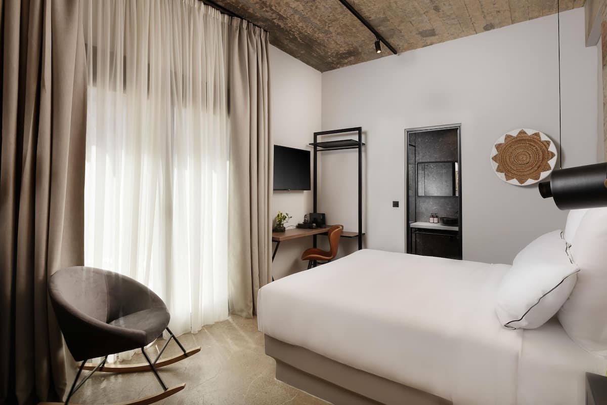 Una moderna camera d'albergo con un letto, una scrivania, una sedia e una televisione.
