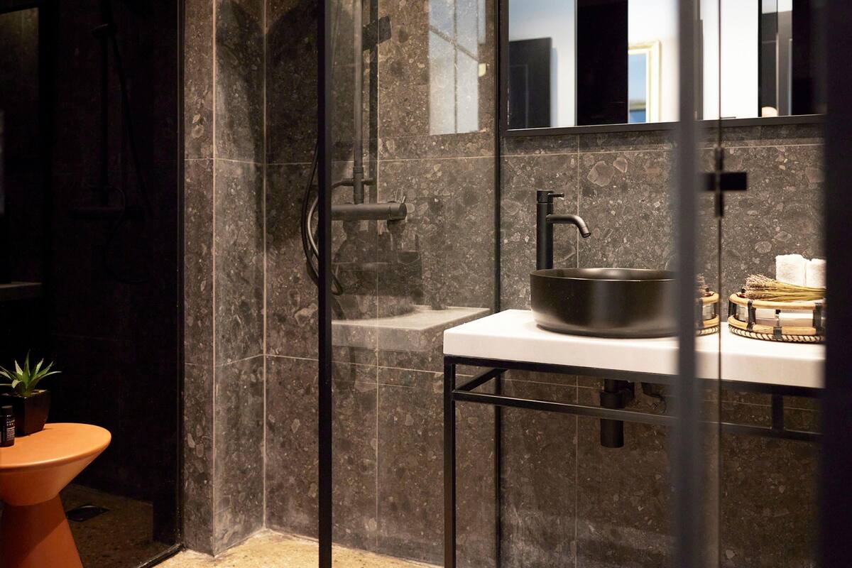 Een moderne badkamer met een douchecabine van glas, een wastafel met een kuipwastafel en een kleine potplant.