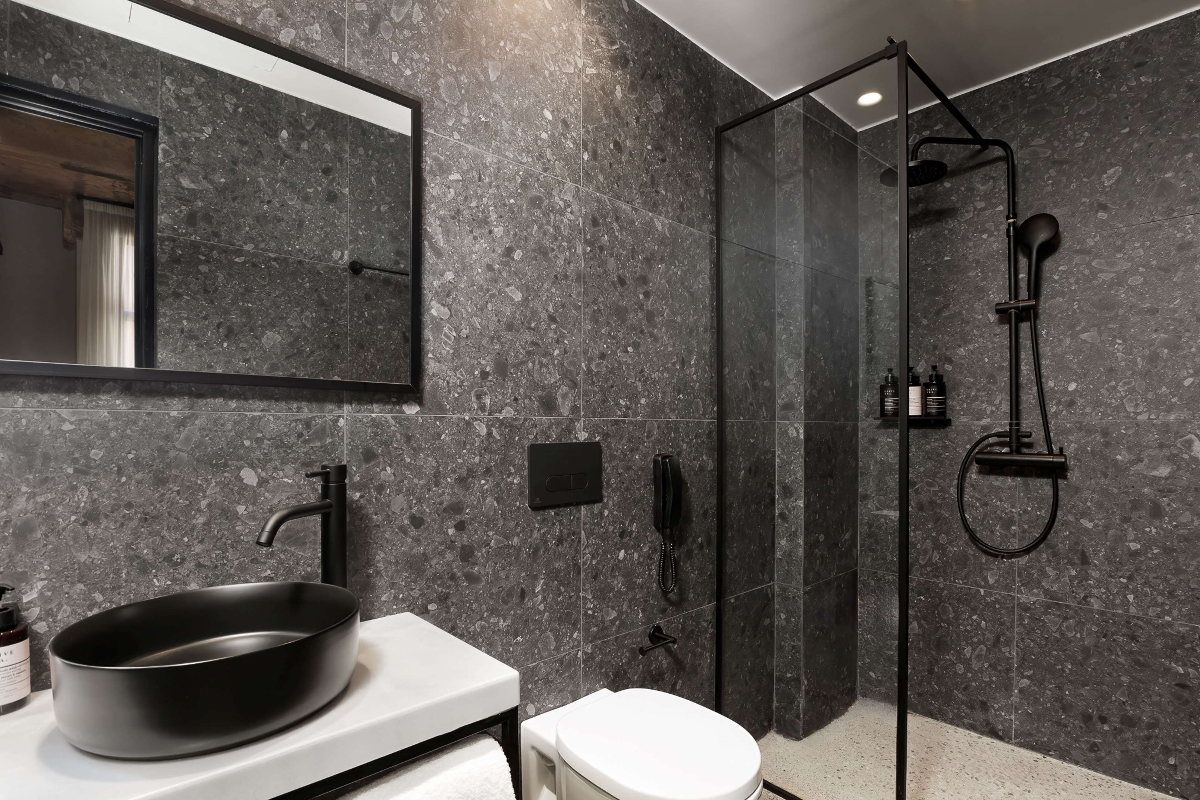 A modern bathroom with a large oval sink, a toilet, and a glass-enclosed shower area.