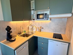 A compact kitchen with a coffee maker, sink, microwave, and a dishwasher.