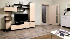 Een moderne woonkamer met een flatscreen televisie, inbouwkasten en een lichtkleurige garderobe.