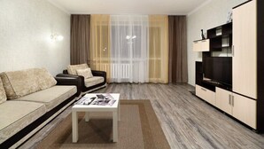 Een woonkamer met een bank, een salontafel, een televisie en een kast.