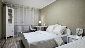 Een hotelkamer met een bed, nachtkastjes, een bureau, een stoel en een kledingkast.