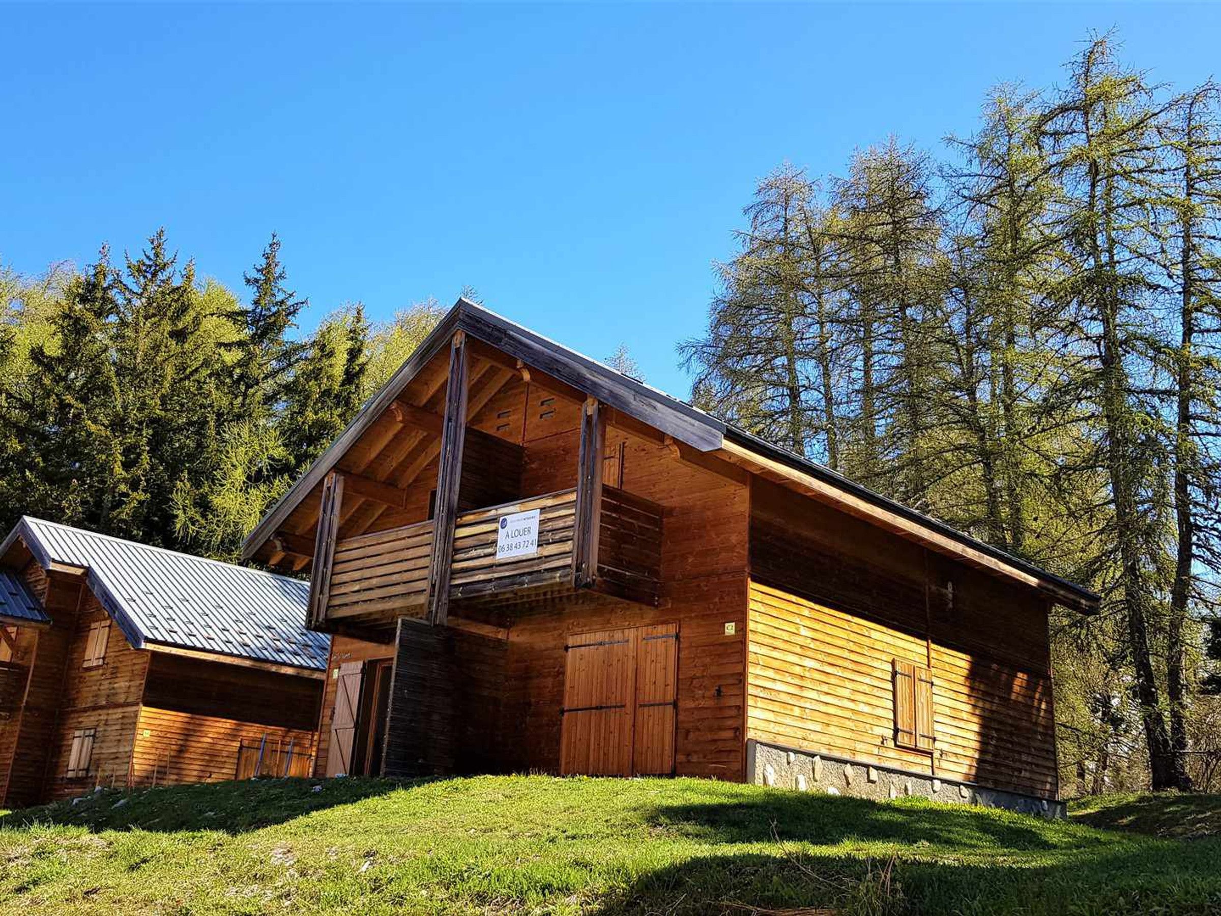 A wooden cabin with a balcony, surrounded by trees.