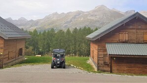 Eine Holzhütte mit einem Schotterweg und einem geparkten Fahrzeug davor.