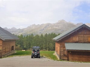 Eine Holzhütte mit einem Schotterweg und einem geparkten Fahrzeug davor.