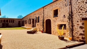 A building with a stone facade, multiple windows, and a gravel courtyard. - Two Historic Holiday Homes in the Dordogne — Each with a Private Heated Pool (Capdrot)