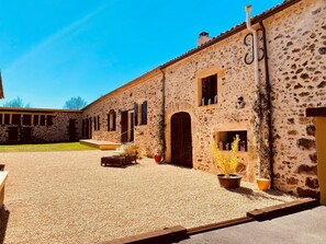 A building with a stone facade, multiple windows, and a gravel courtyard.