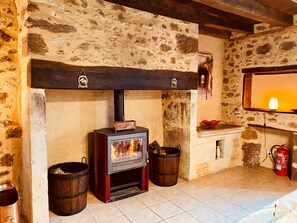 A stone-walled room with a wood-burning stove, two wooden barrels, and a fire extinguisher. - 4* Holiday Homes with aircon and Private Heated Pools - 5 Mins from Monpazier (Capdrot)
