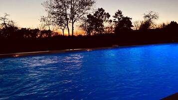 A swimming pool at dusk with trees in the background.