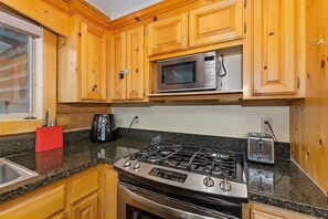 Una cocina con armarios de madera, estufa a gas, microondas y tostadora.