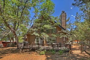 A log cabin with a chimney, surrounded by trees and a fenced yard.