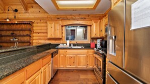 Cocina estilo cabaña de madera con una isla grande, electrodomésticos de acero inoxidable y un tragaluz.