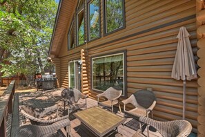 A log cabin with a patio area featuring wicker furniture and a grill.