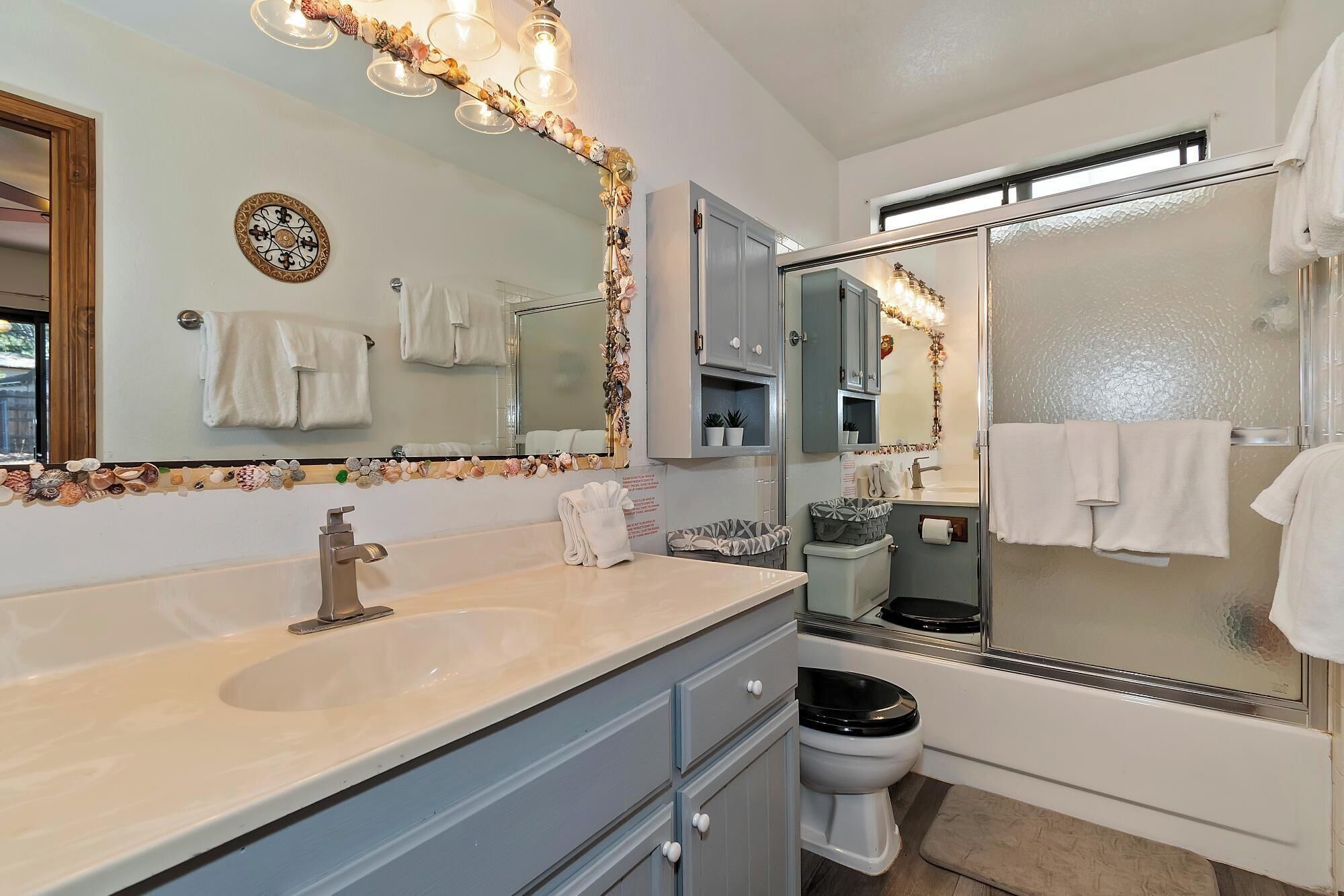 Un bagno con un grande specchio, un lavandino, un water e una zona doccia.