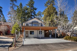 A two-story building with a covered patio area and a fenced parking lot.