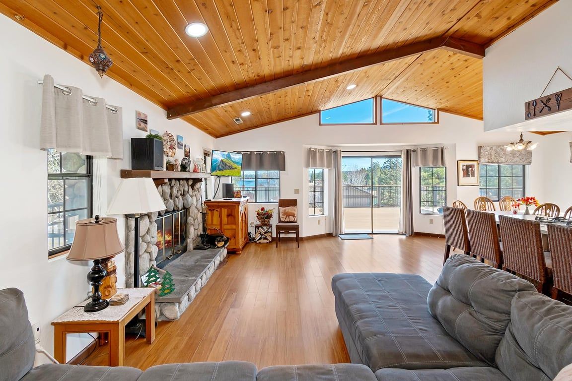 A spacious living room with a high ceiling, a fireplace, a sofa, and a dining area with chairs.