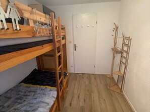 A room with bunk beds, a door, and a wooden shelf unit.