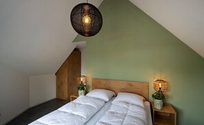 A bedroom with a sloped ceiling, a wooden headboard, two bedside tables with lamps, and a bed with white bedding. - Sprielderbosch 10 in ruhiger Lage in einem Luxuspark in der Nähe von Garderen (Putten)
