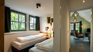 A bedroom with two beds, large windows, a ceiling light, and a view of the outdoors. - Sprielderbosch 10 quietly located in a luxury park near Garderen (Putten)