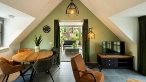 A dining area with a round table, chairs, a potted plant, and a clock on the wall. - Sprielderbosch 10 quietly located in a luxury park near Garderen (Putten)