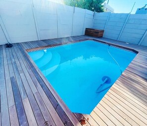 Une piscine rectangulaire entourée d’une terrasse en bois.