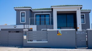 A modern building with a gated entrance, a security camera, and a sign indicating armed response. - SERENITY @  ITS HEIGHTS (Cape Town)