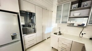 A modern kitchen with stainless steel appliances, white cabinetry, and a built-in sink. - SERENITY @  ITS HEIGHTS (Cape Town)