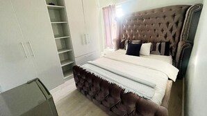 A bedroom with a large bed, a wardrobe, and a built-in shelf unit. - SERENITY @  ITS HEIGHTS (Cape Town)