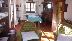 A dining area with a table set for four, a green armchair with a white pillow, and a wooden cabinet with glass doors. - Unique chalet for 8 ppl, pets welcome, parking (Les Contamines-Montjoie)