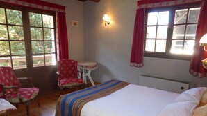 A bedroom with a wooden bed, a small table, two chairs, and large windows with red curtains. - Unique chalet for 8 ppl, pets welcome, parking (Les Contamines-Montjoie)