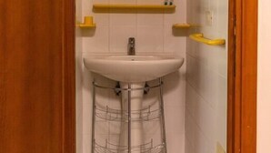A small bathroom with a white sink, a mirror, and a yellow towel rack.