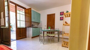 A compact kitchen with a dining area, wooden cabinets, and a small table with chairs.