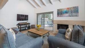 A modern living room with a fireplace, a TV, and a painting on the wall. - Seasonal Pool and Year-Round Hot Tub (Sun Valley)