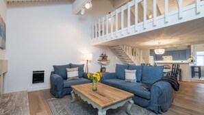 A spacious living area with a wooden coffee table, two blue sofas, and a staircase leading to an upper level. - Seasonal Pool and Year-Round Hot Tub (Sun Valley)