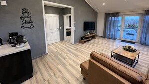 Una sala de estar moderna con sofá, cafetera, televisor y vistas al exterior.