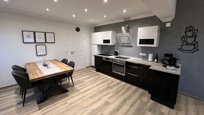 Una cocina moderna con una mesa de comedor de madera, sillas negras y electrodomésticos de acero inoxidable.