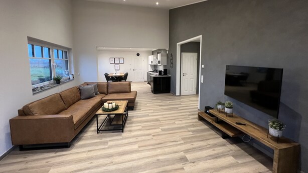 Una sala moderna con un sofá modular, una mesa de centro y un televisor sobre un mueble.