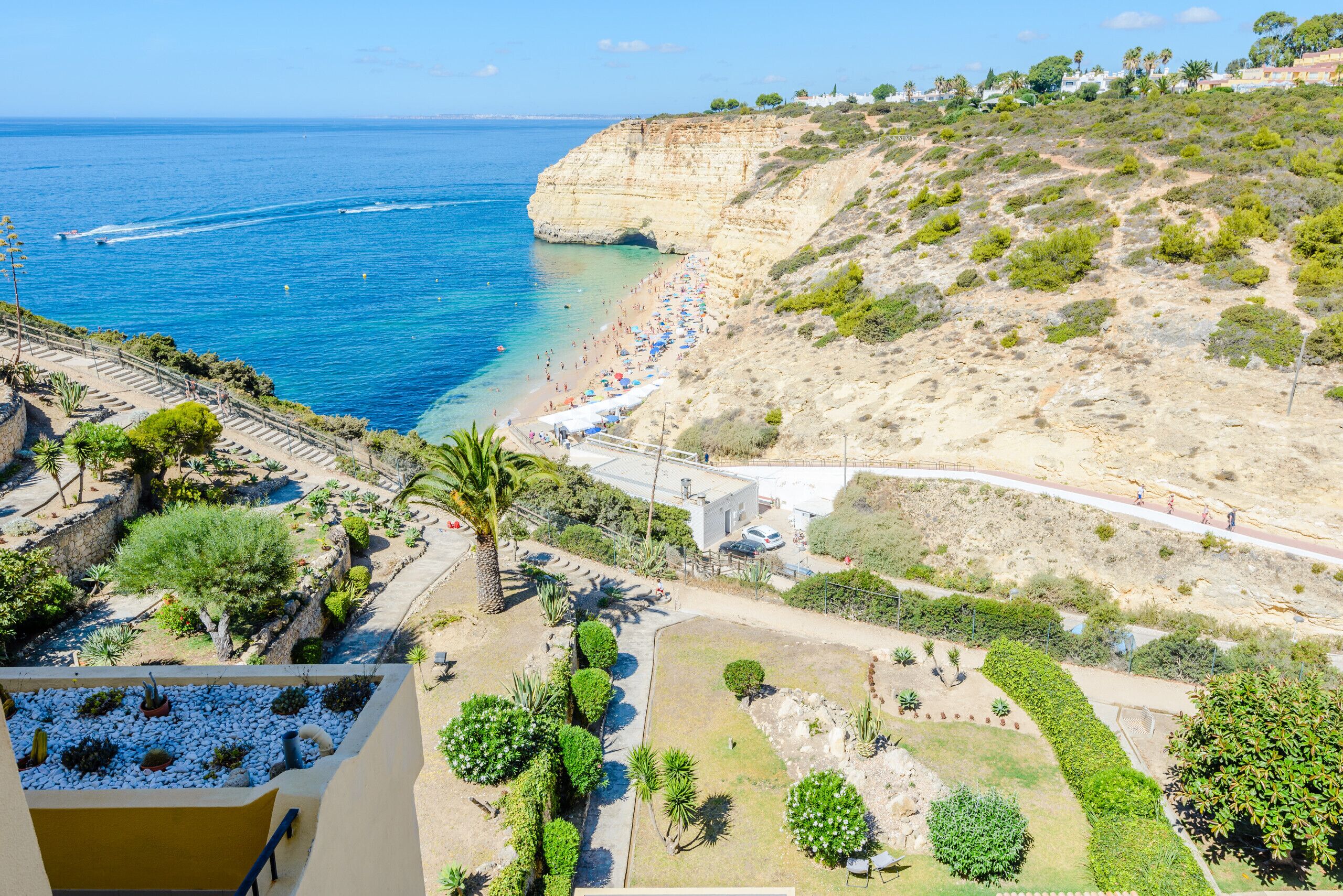 A coastal resort with a beach, cliffside, and landscaped gardens.