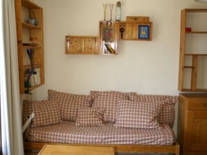 A cozy room with a checkered sofa, wooden shelves, and a cabinet. - 2-room cabin apartment at the foot of the slopes with balcony (Les Adrets-Prapoutel)