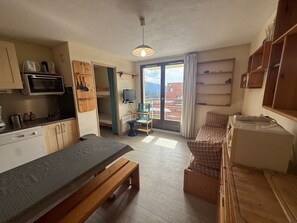 Une pièce compacte comprenant un coin cuisine, un lit, une petite table et un téléviseur.