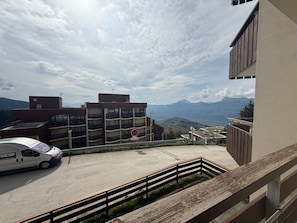 Un'area di parcheggio con un'auto bianca, un segnale di divieto di sosta e montagne sullo sfondo.