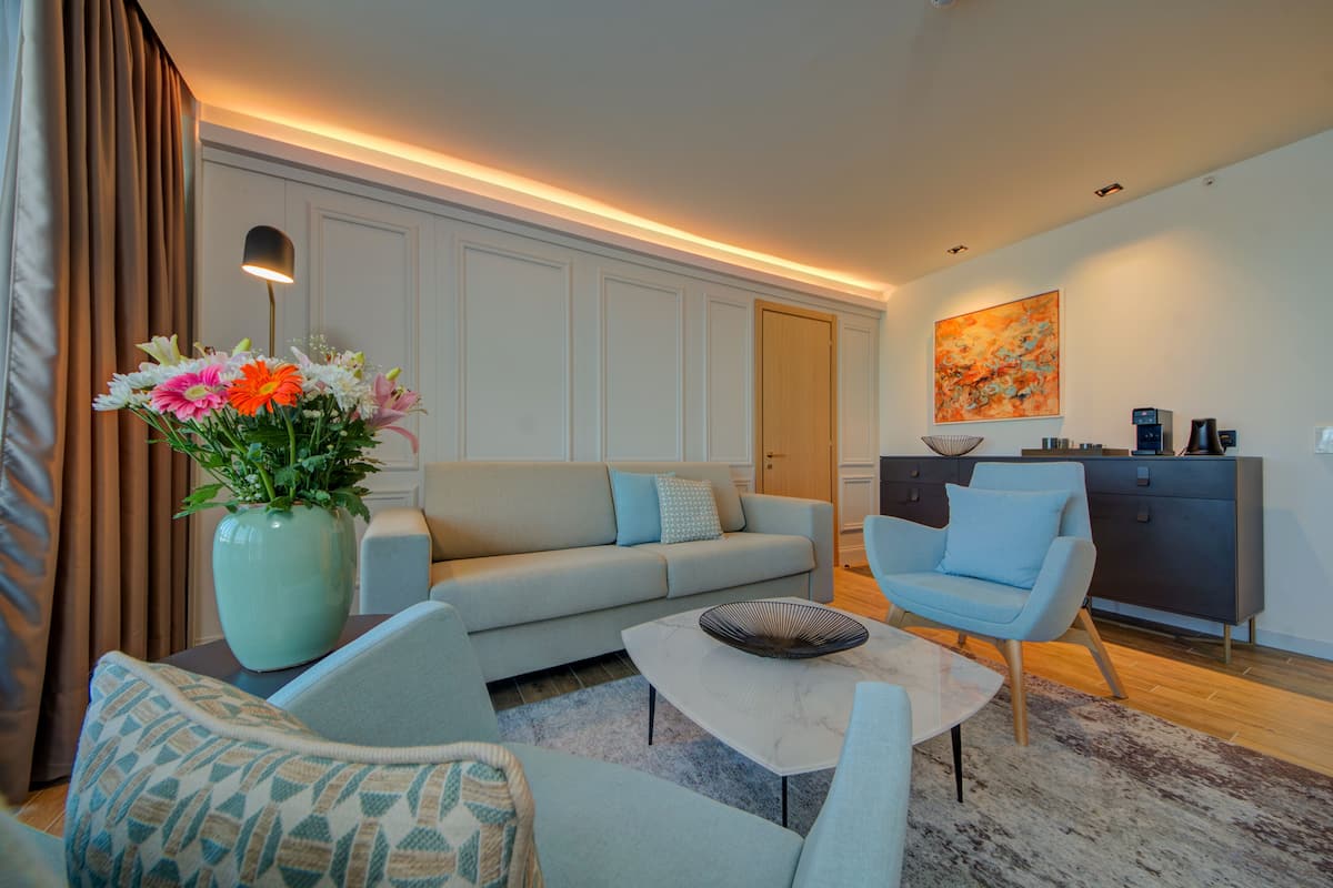 A modern living room with a sofa, armchairs, a coffee table, and a vase of flowers.