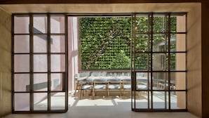 A room with a large window, a wooden floor, and a dining area with tables and chairs. - Land's End Boutique Hotel (Sliema)