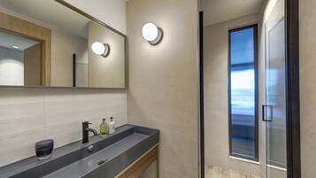 A modern bathroom with a large mirror, a sink with a soap dispenser, and a glass shower enclosure.