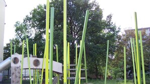 A playground with green poles and a wooden climbing structure.