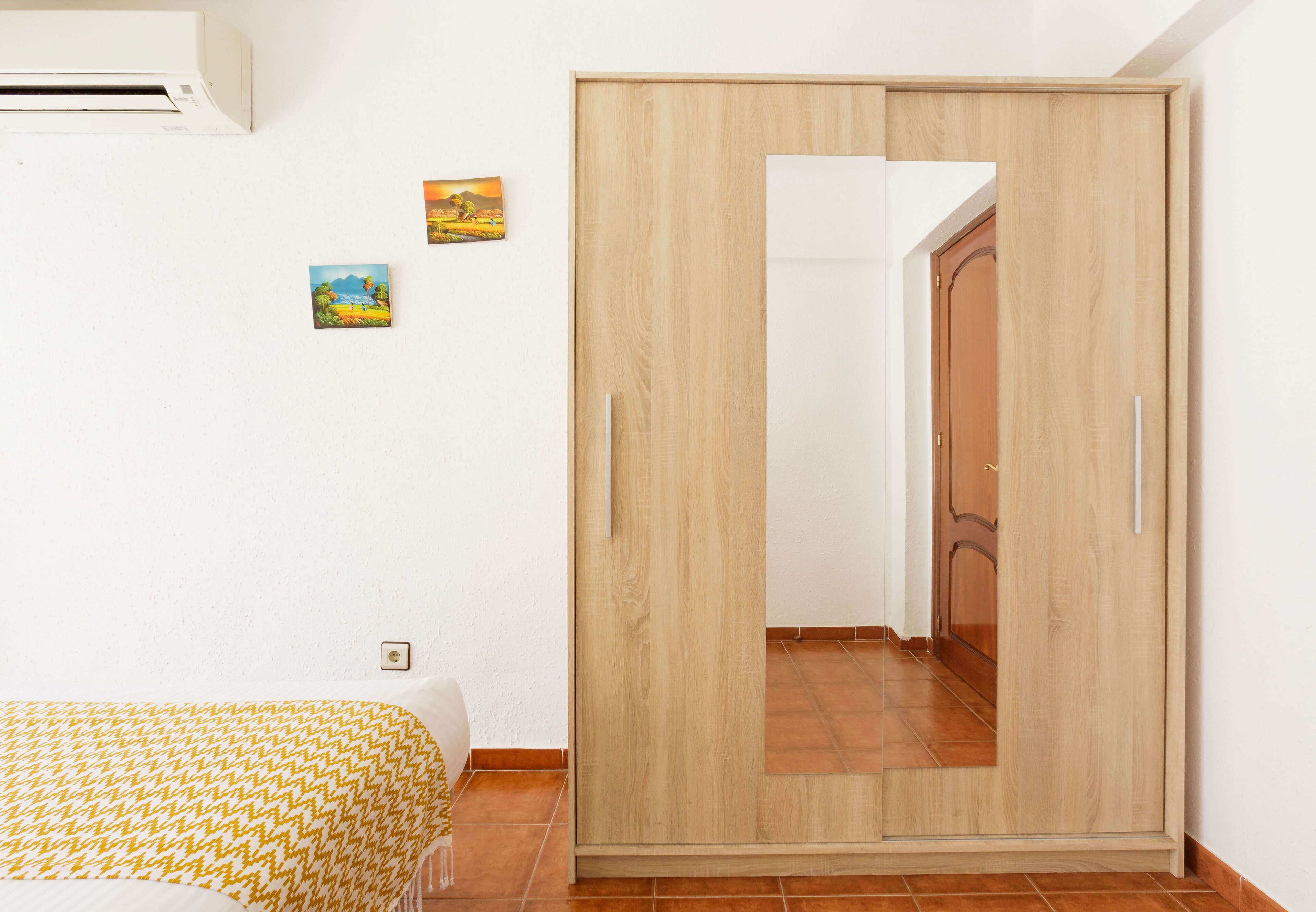 Quarto com uma cama, um guarda-roupa e uma pequena pintura na parede.