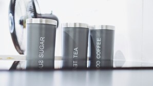 Three stainless steel containers labeled "SUGAR," "TEA," and "COFFEE" on a reflective surface. - Onsite Cosy Practical Studio - in a Quite Area (Coventry)