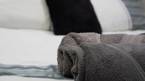 A bed with a grey blanket and pillows. - Onsite Cosy Practical Studio - in a Quite Area (Coventry)